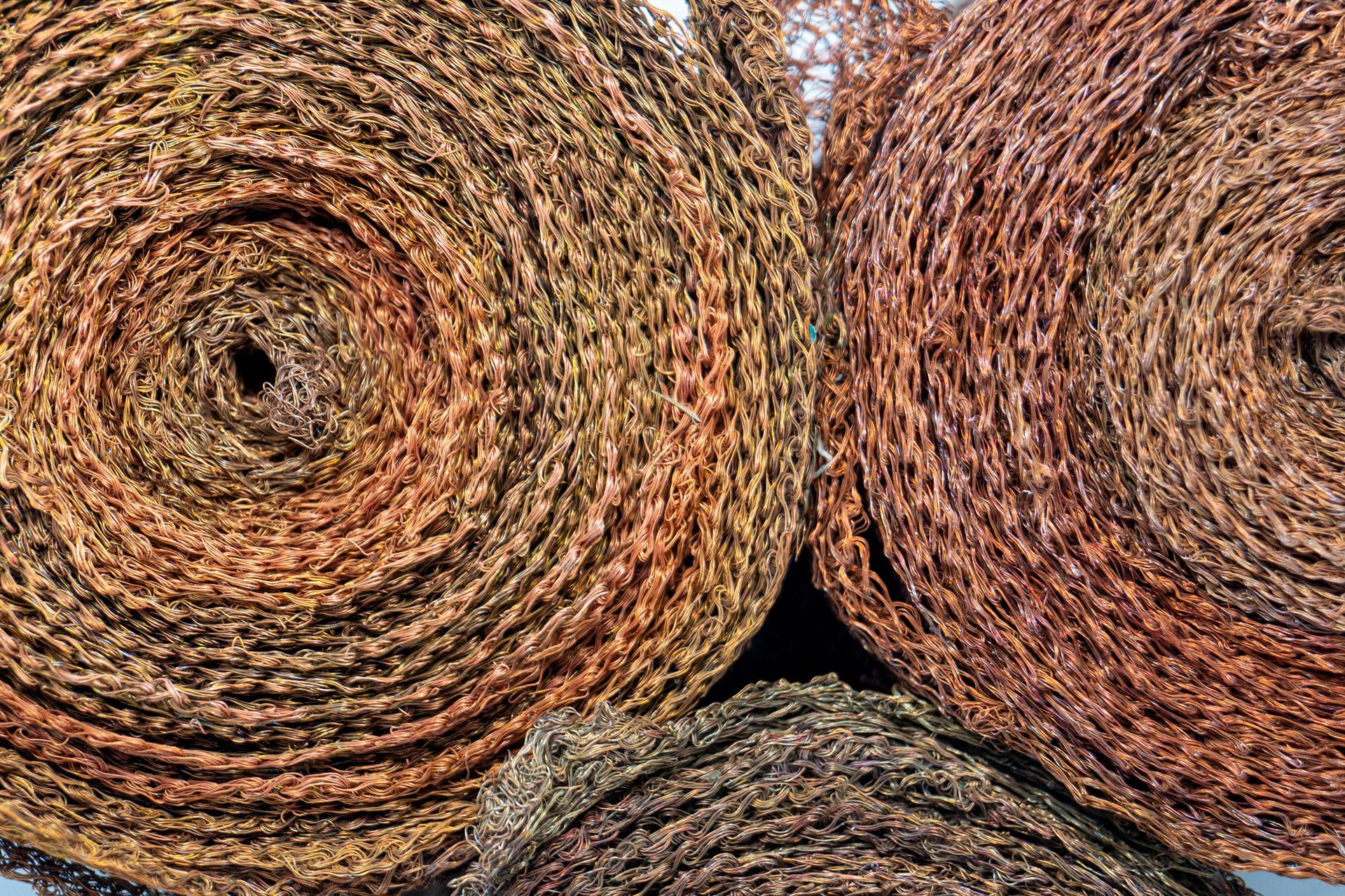 A close-up of rolls of copper mesh is displayed in a pile.