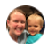 Woman smiling with a child, both looking at the camera.