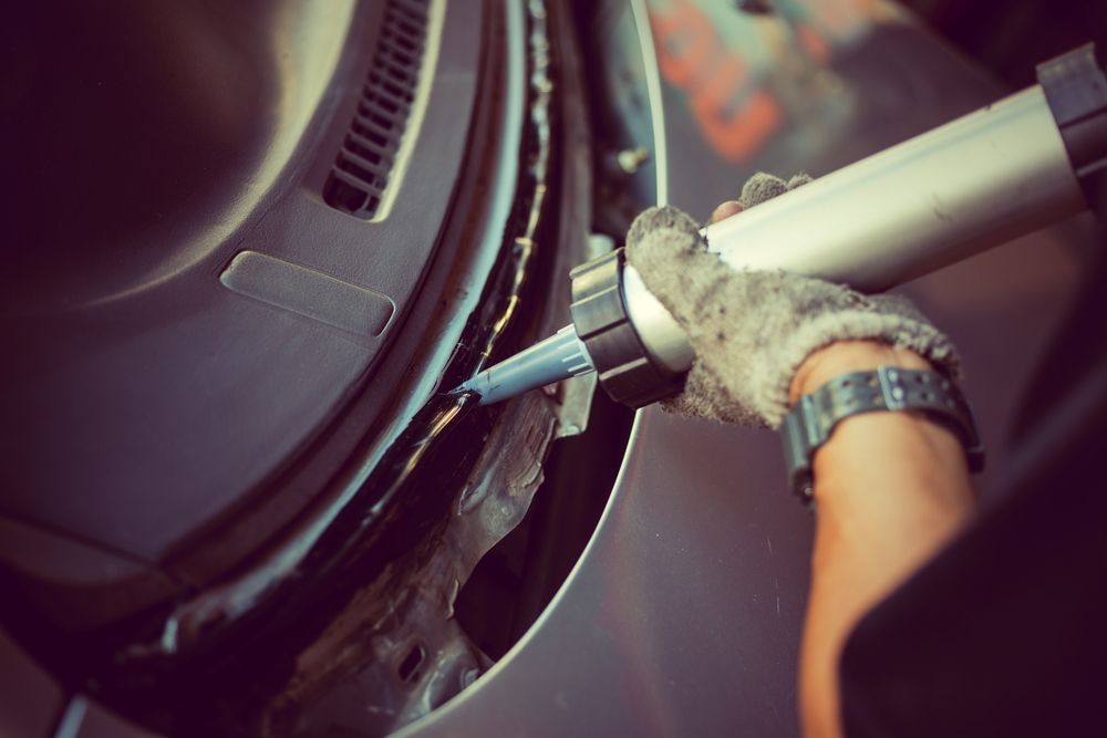 A Person Is Applying Sealant To A Car Door — Raymond Terrace Windscreen Services In Raymond Terrace, NSW