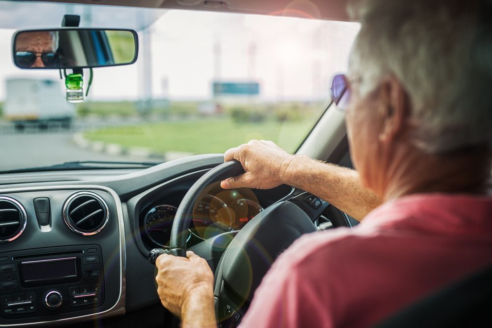 An Older Man Is Driving A Car On A Highway — Raymond Terrace Windscreen Services In Lake Macquarie, NSW