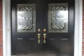 A black double door with stained glass windows on a brick building.