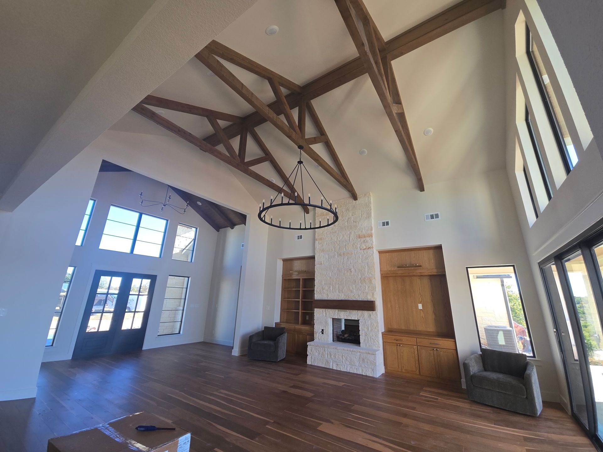 Spacious living room with exposed wood beams, white walls, fireplace, and large windows.