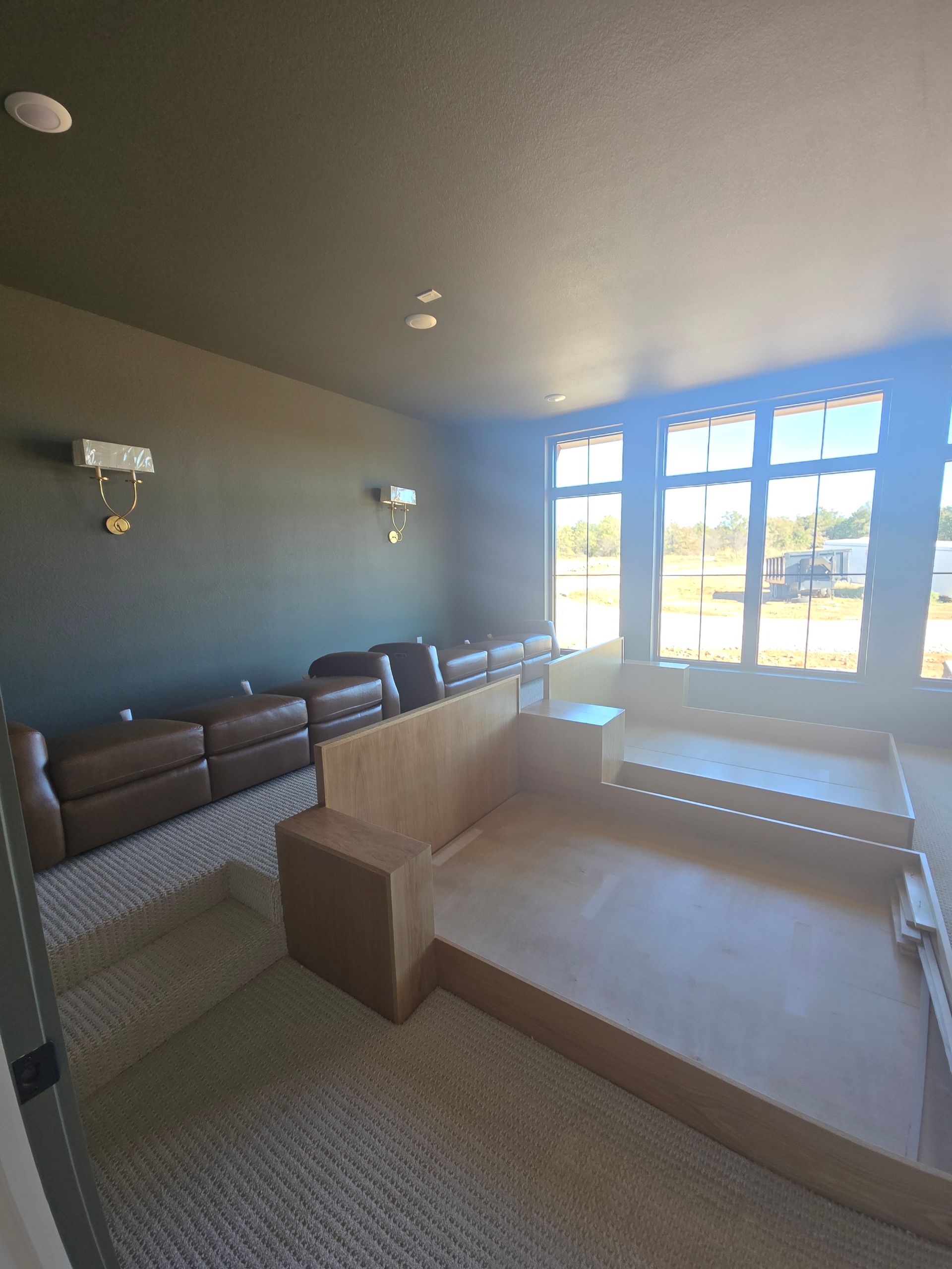 Empty waiting room with brown benches, beige carpet, and bright sunlight through large windows.