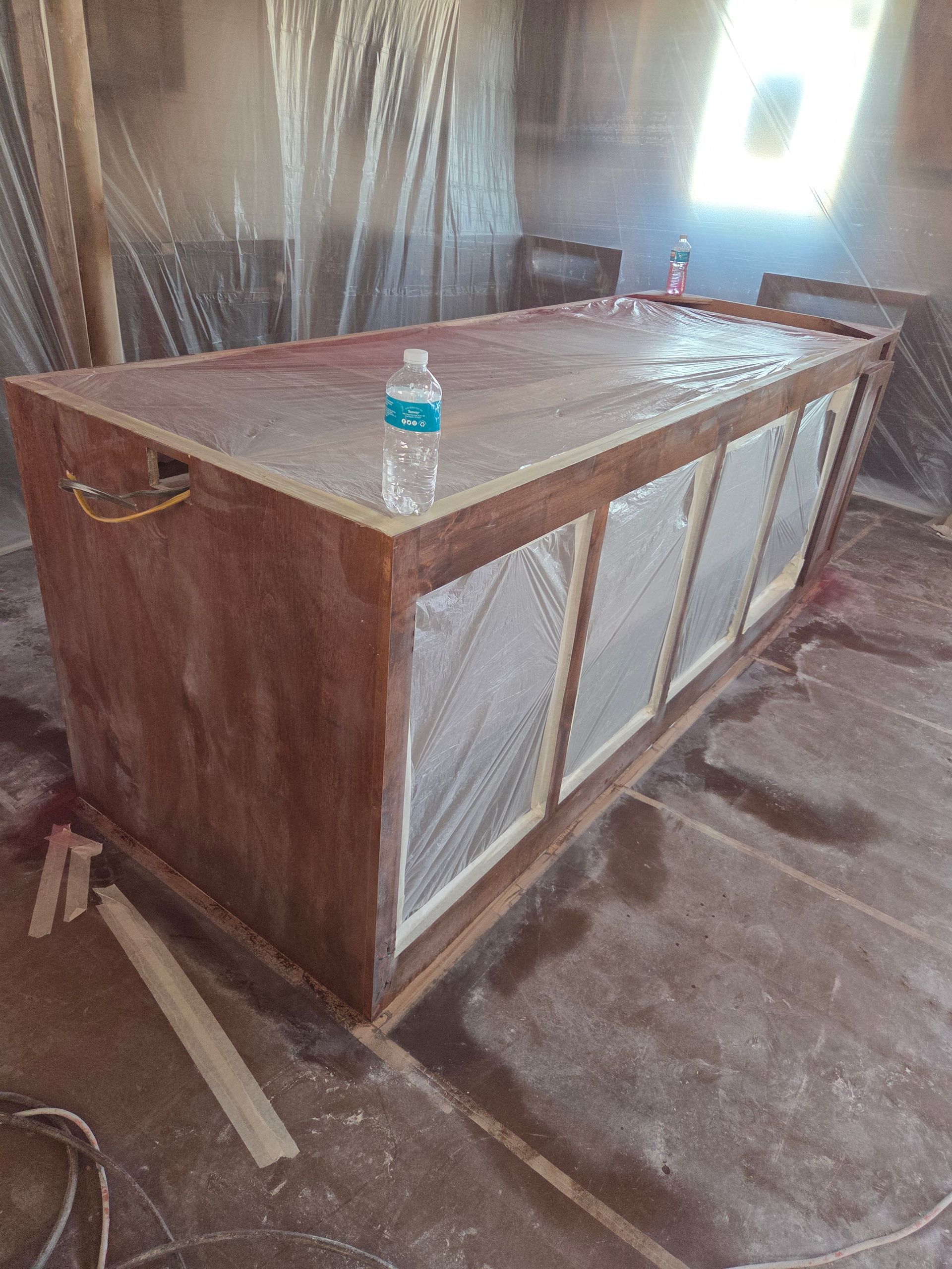 Wooden cabinet with metal mesh panels in a workshop, with a water bottle on top.