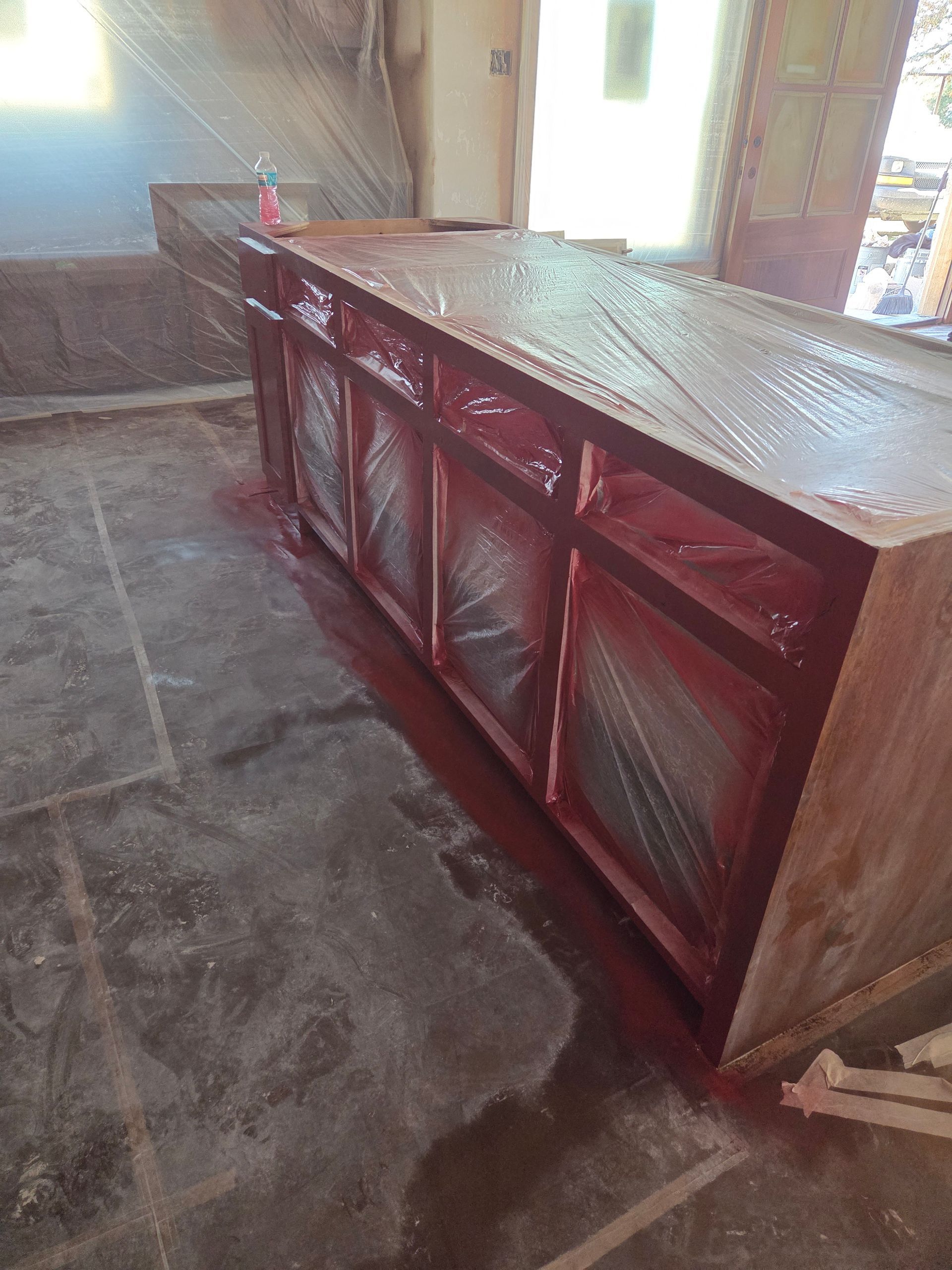 Red counter or cabinet with slatted front panels in a rustic room with stone floor and bright windows