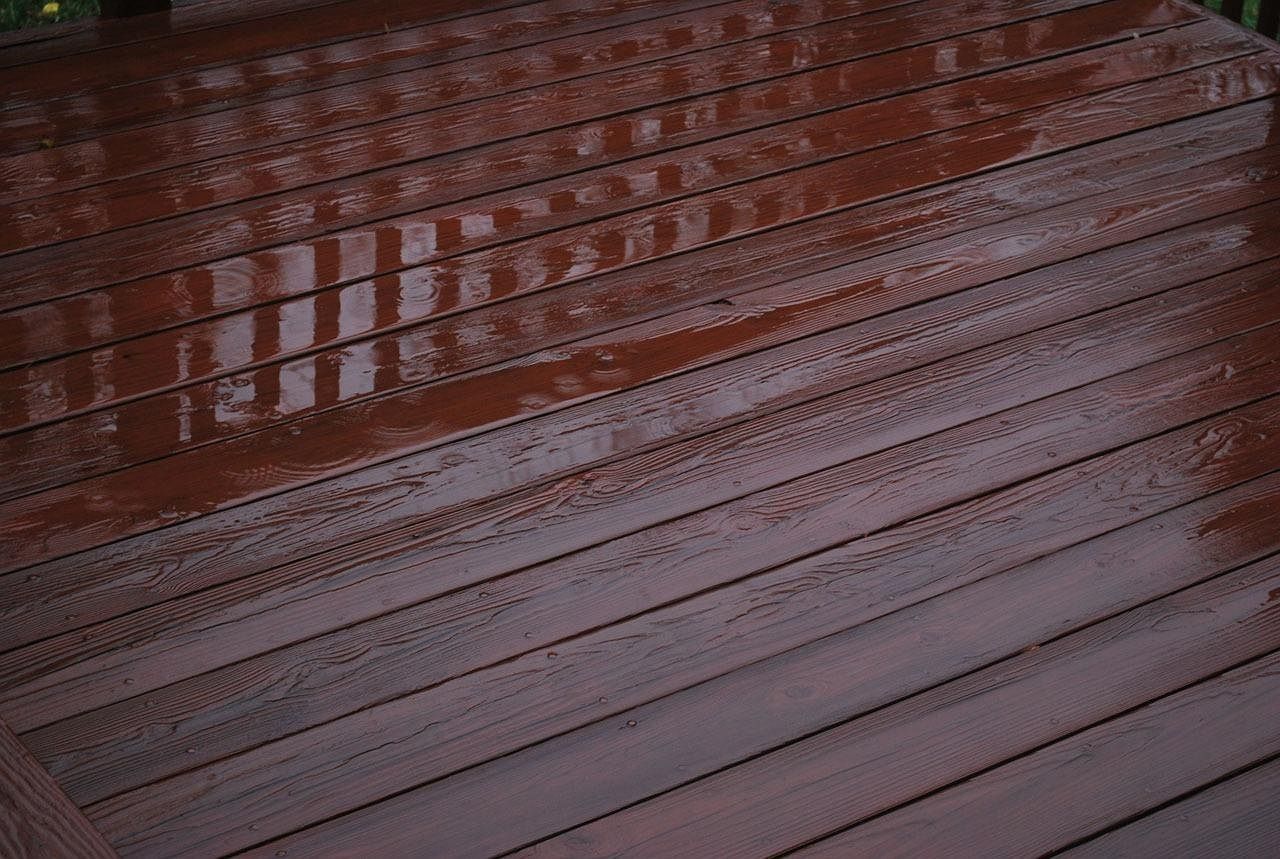A rain-slicked wooden deck with visible tire tracks crossing the wet planks.