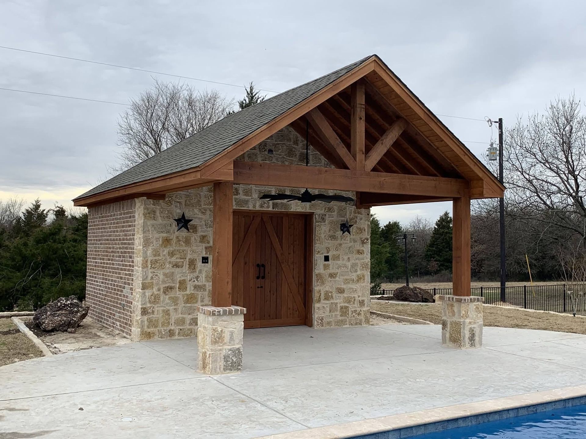 Small stone chapel with a wooden roof and open front porch on a concrete pad outdoors