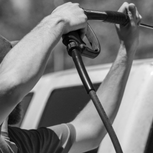 A person uses a pressure washer to clean a vehicle.