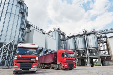two red trucks are parked in front of a silo .