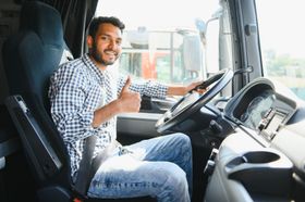 a man is sitting in the driver 's seat of a truck and giving a thumbs up .