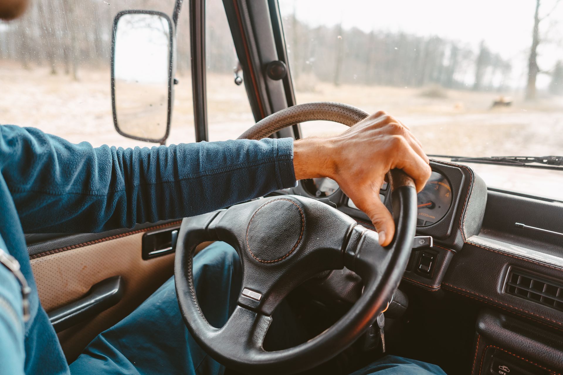 a man is driving a truck with his hand on the steering wheel .