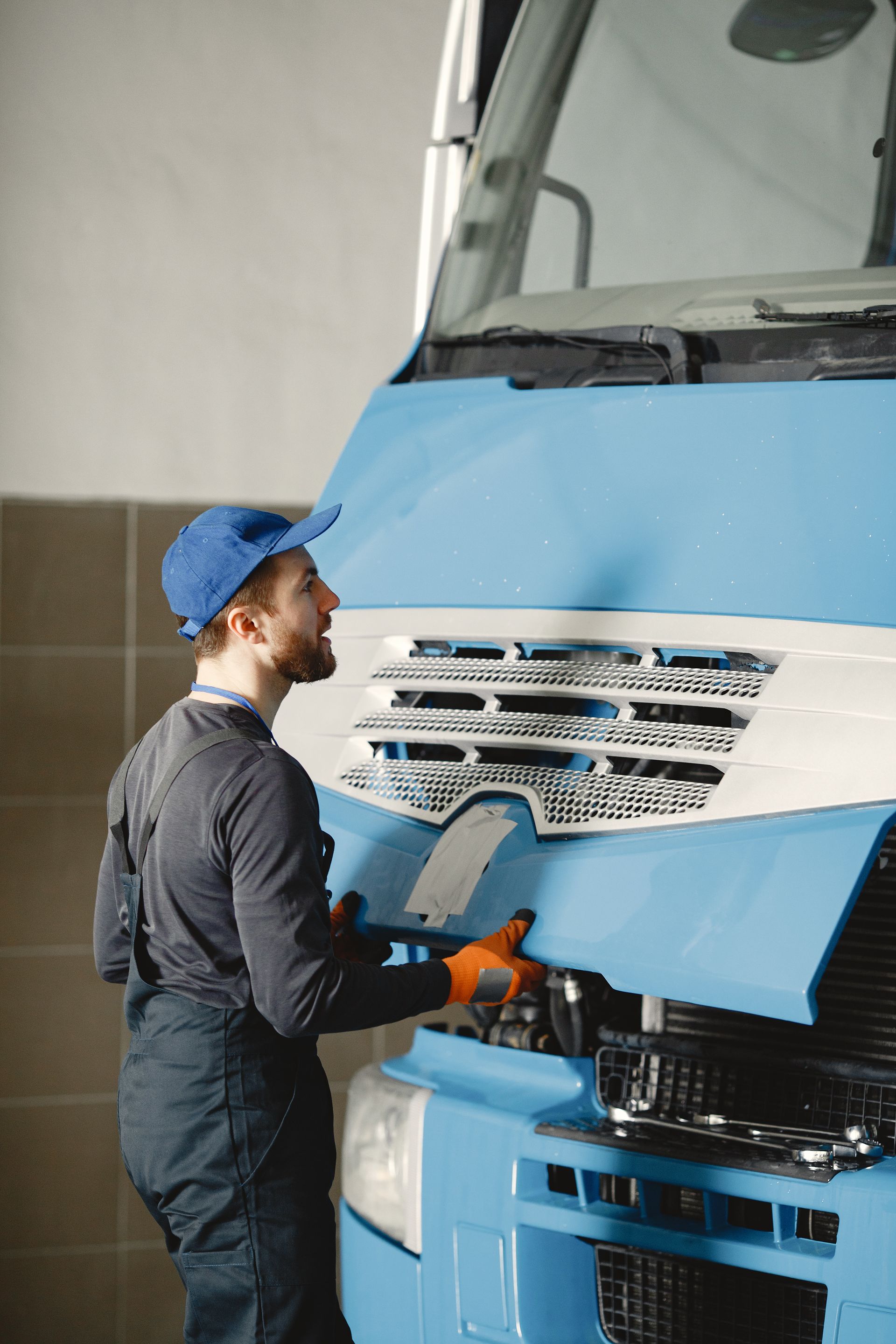 a man is working on the hood of a blue truck .