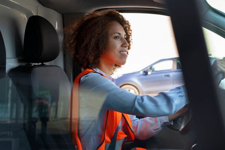 a woman in an orange vest is driving a van .