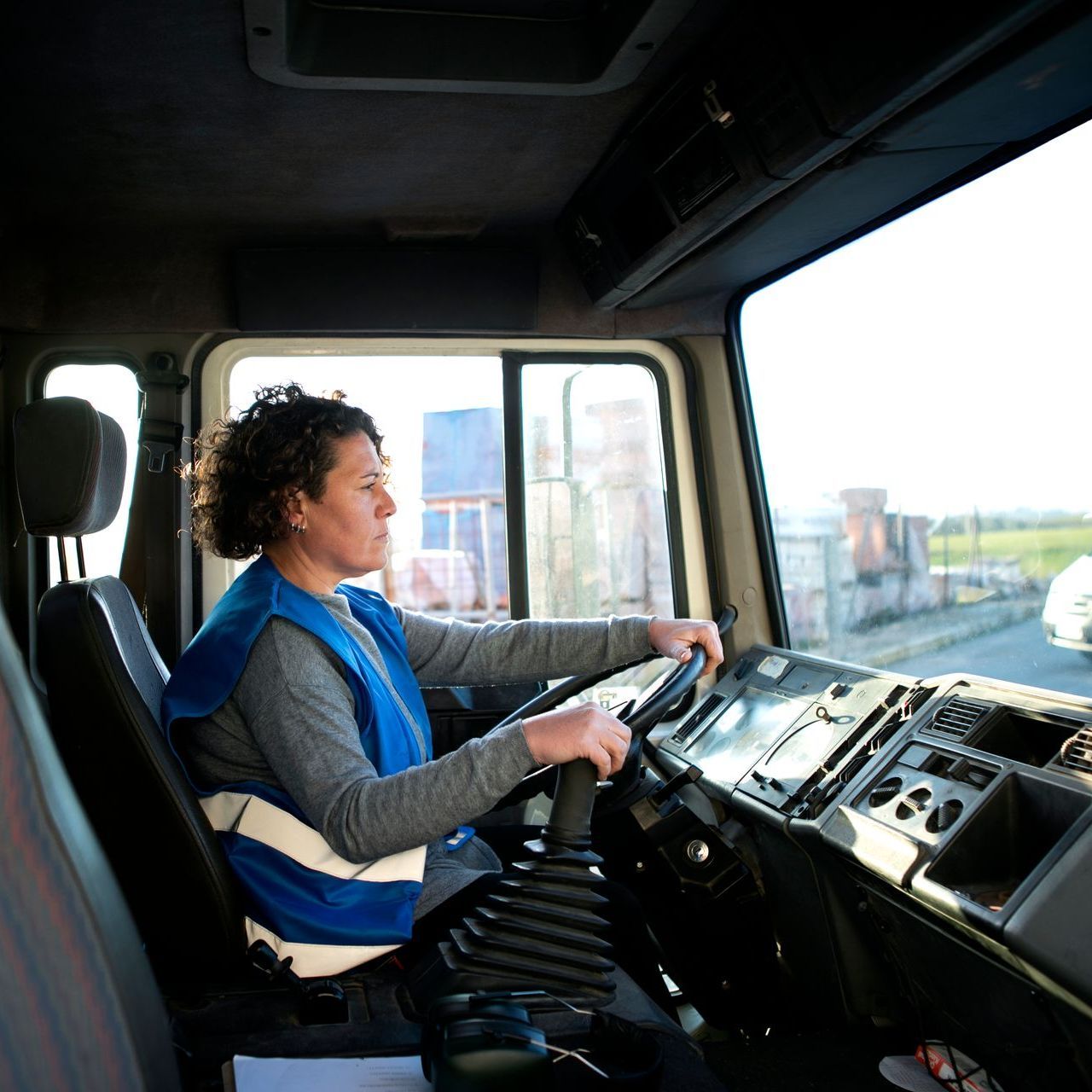 a woman in a blue vest is driving a truck