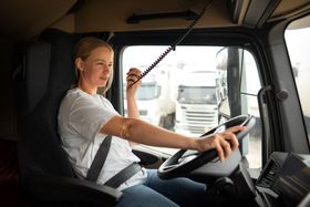 a woman is driving a semi truck and talking on a walkie talkie .