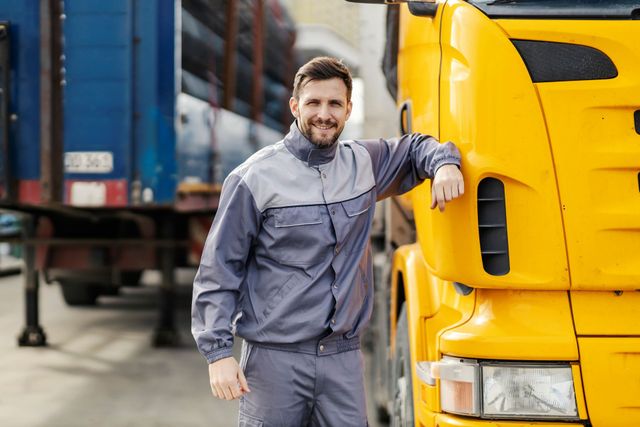 a man is leaning against a yellow truck in a parking lot .