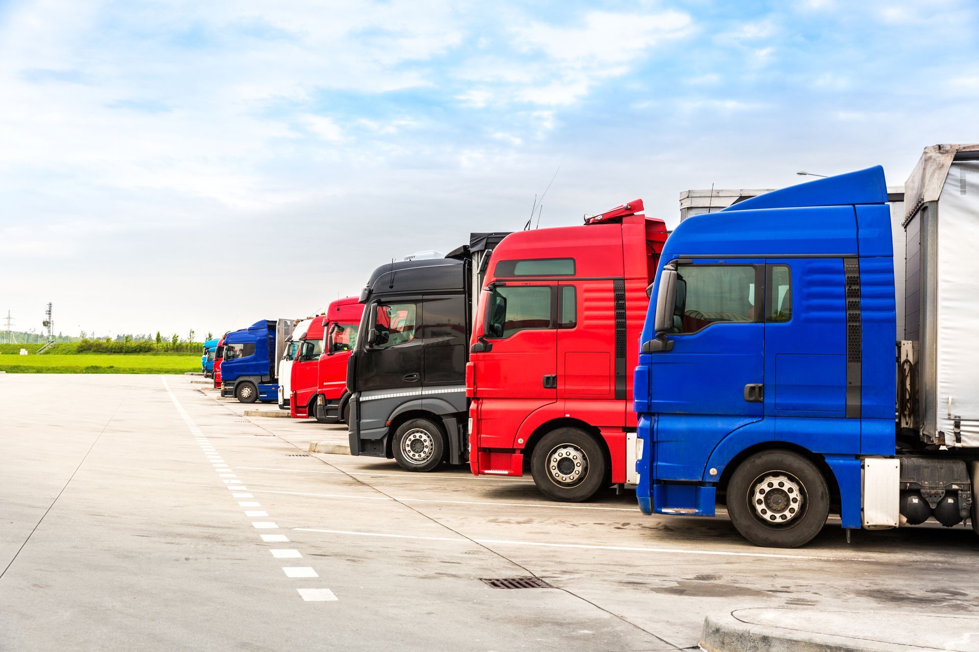 a row of semi trucks parked in a parking lot .