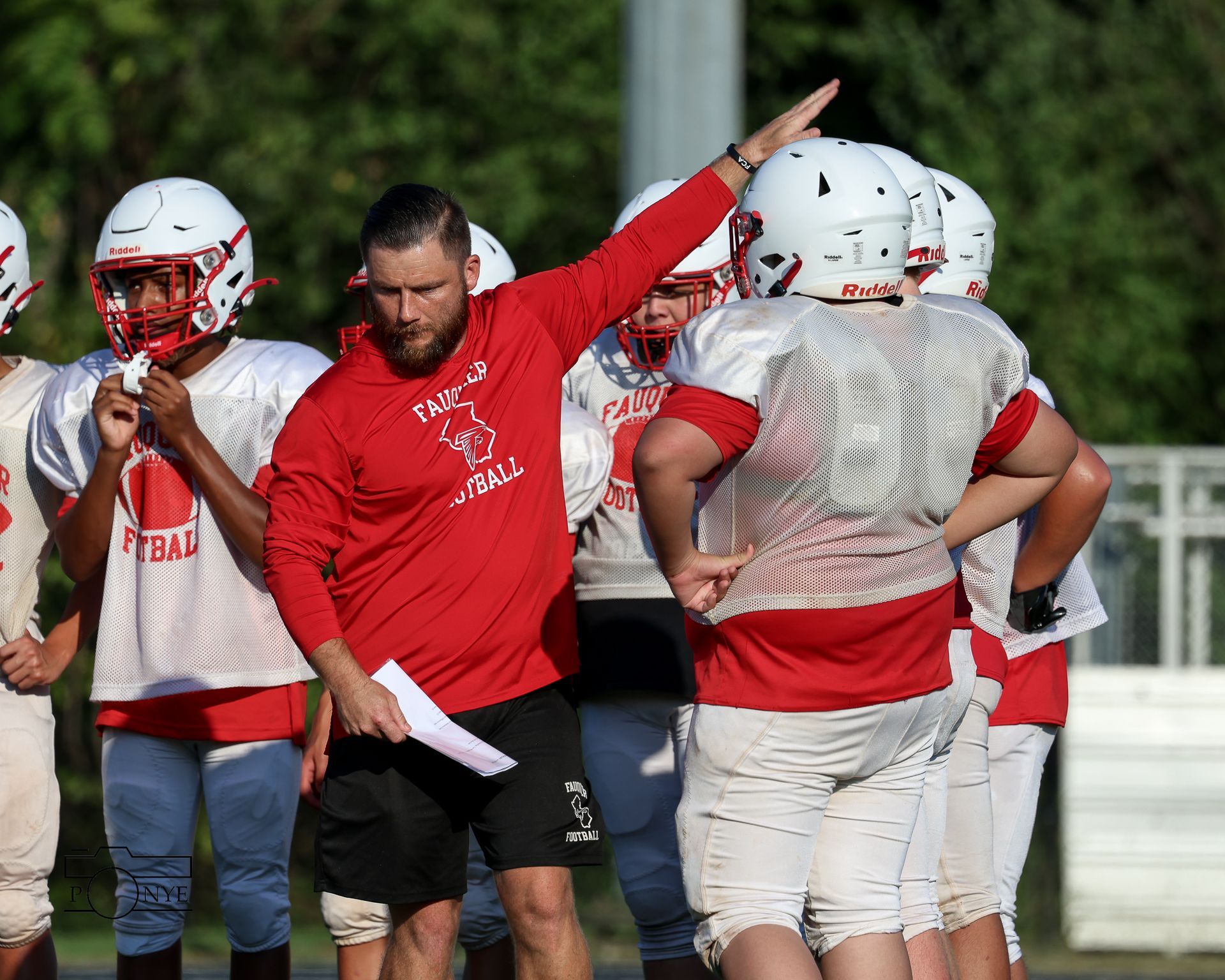 A coach working with football players on the field.