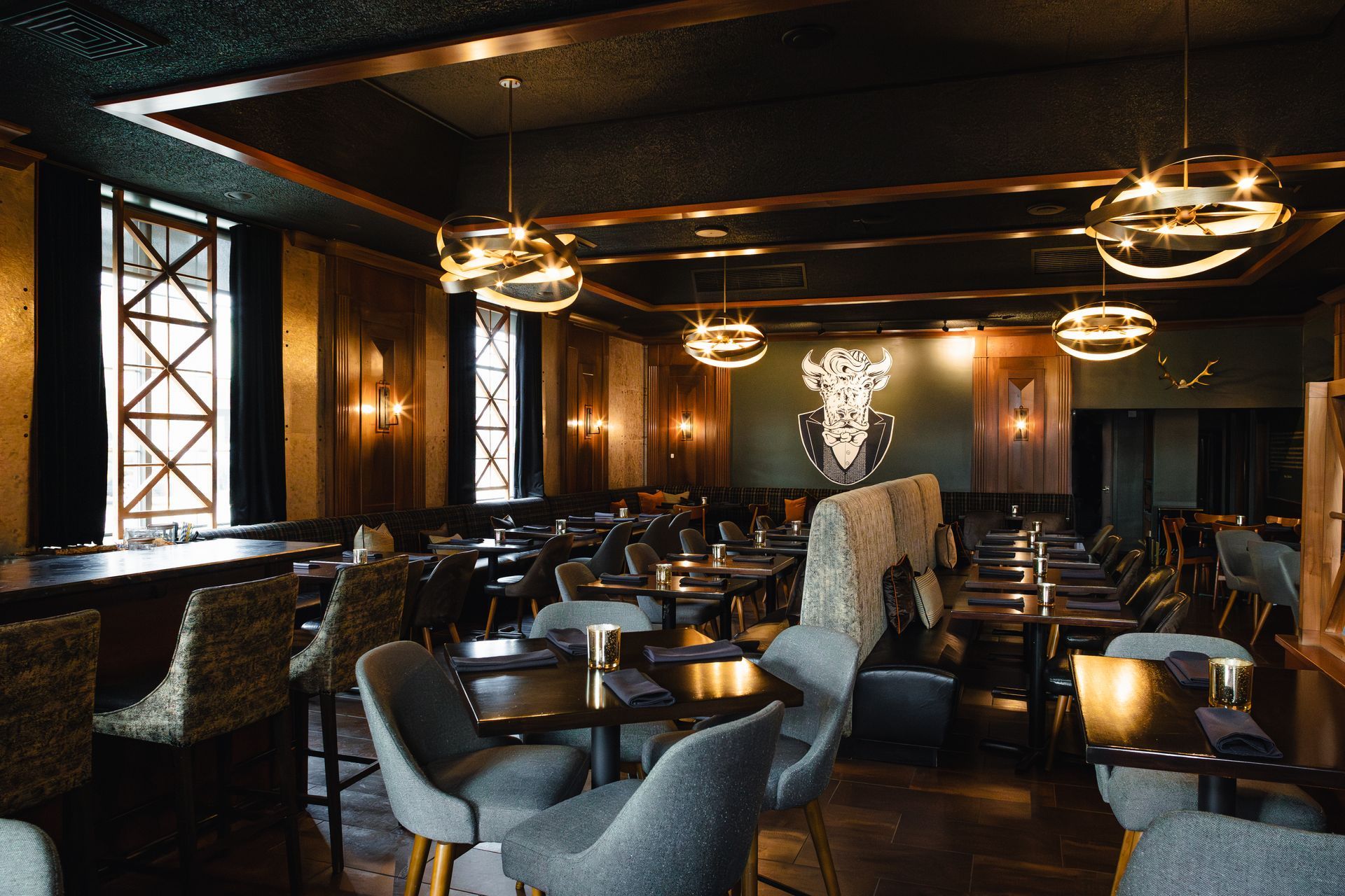 Upscale restaurant interior with dark wood paneling, globe lights, tables, and seating.