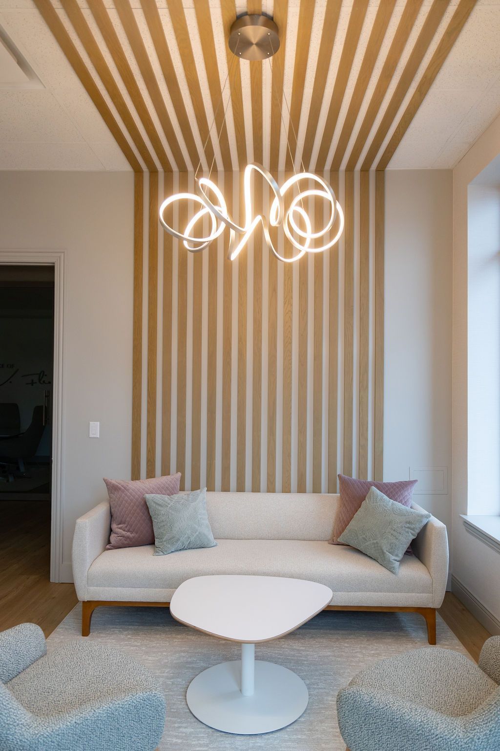 Living room with sofa, pillows, coffee table, and abstract light fixture against wooden paneling.