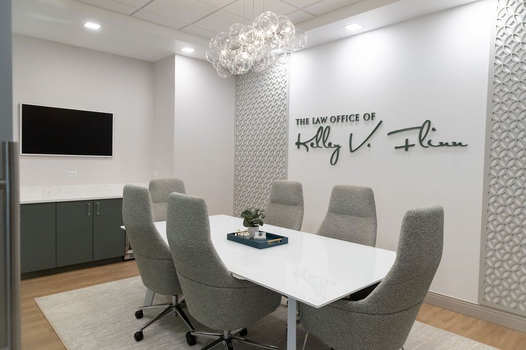 Conference room with a white table, gray chairs, a TV, and decorative wall.