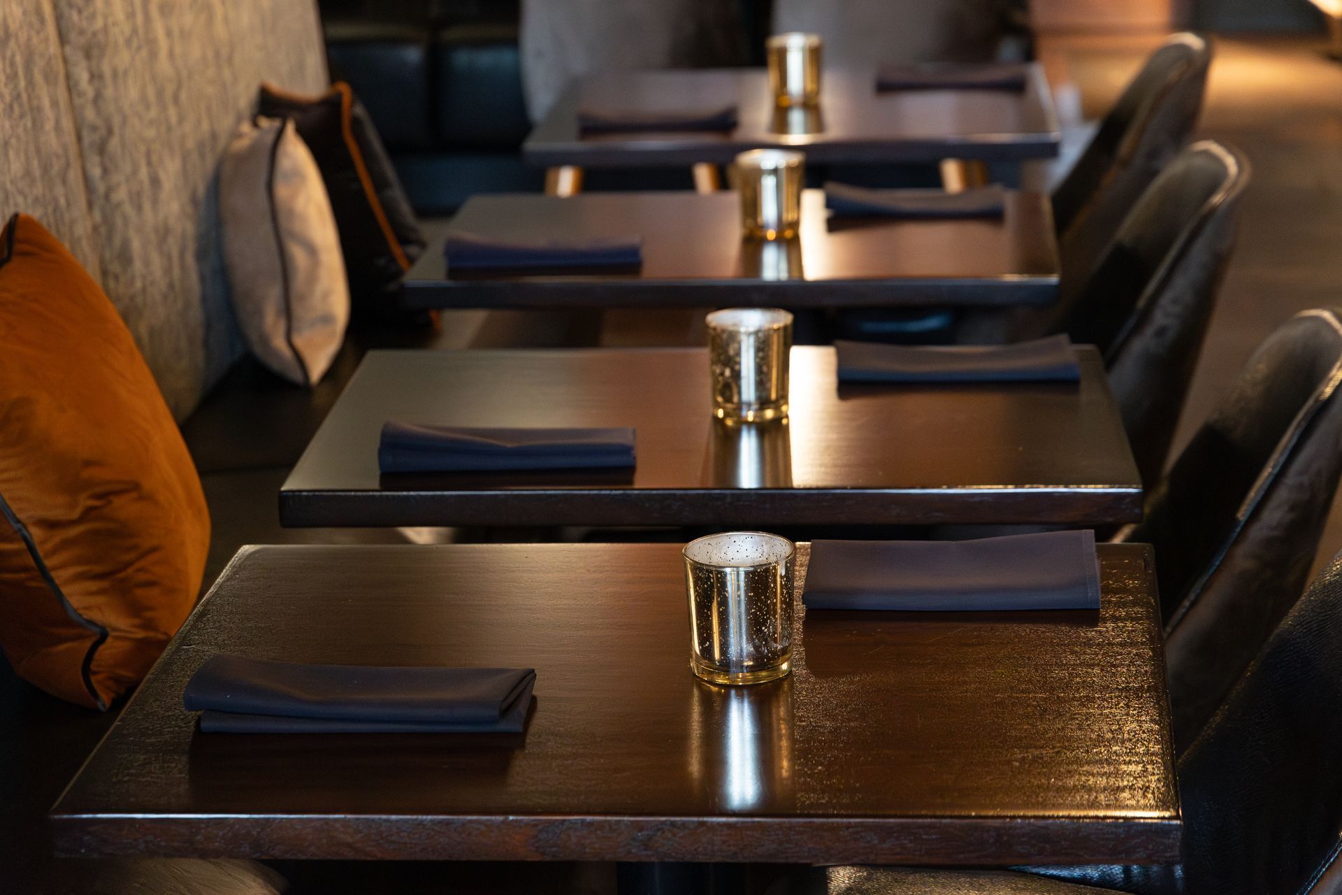 Restaurant dining tables set with napkins and candle holders.