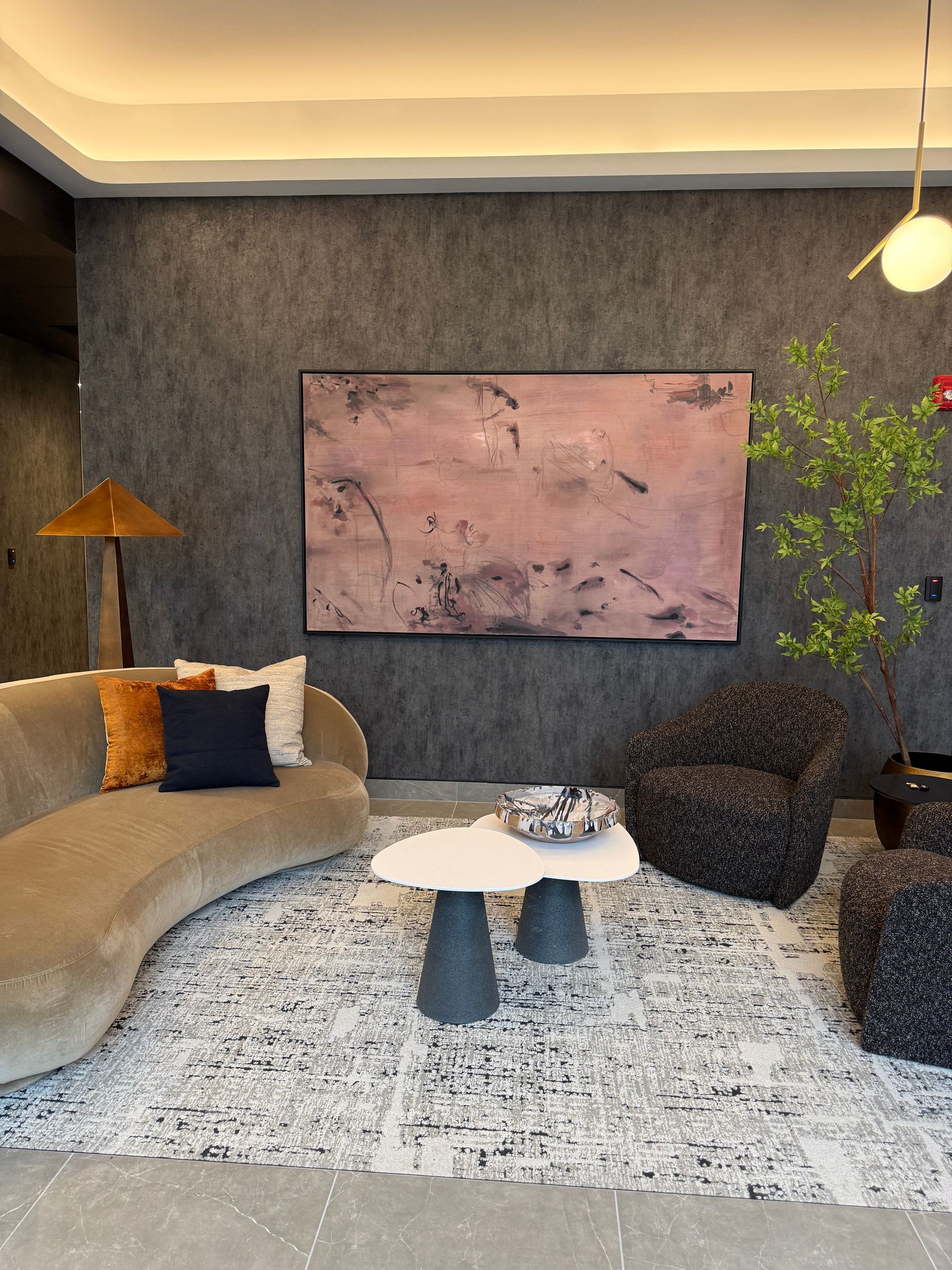 Cozy modern living room with gray sofa, white coffee table, patterned rug, and abstract wall art.