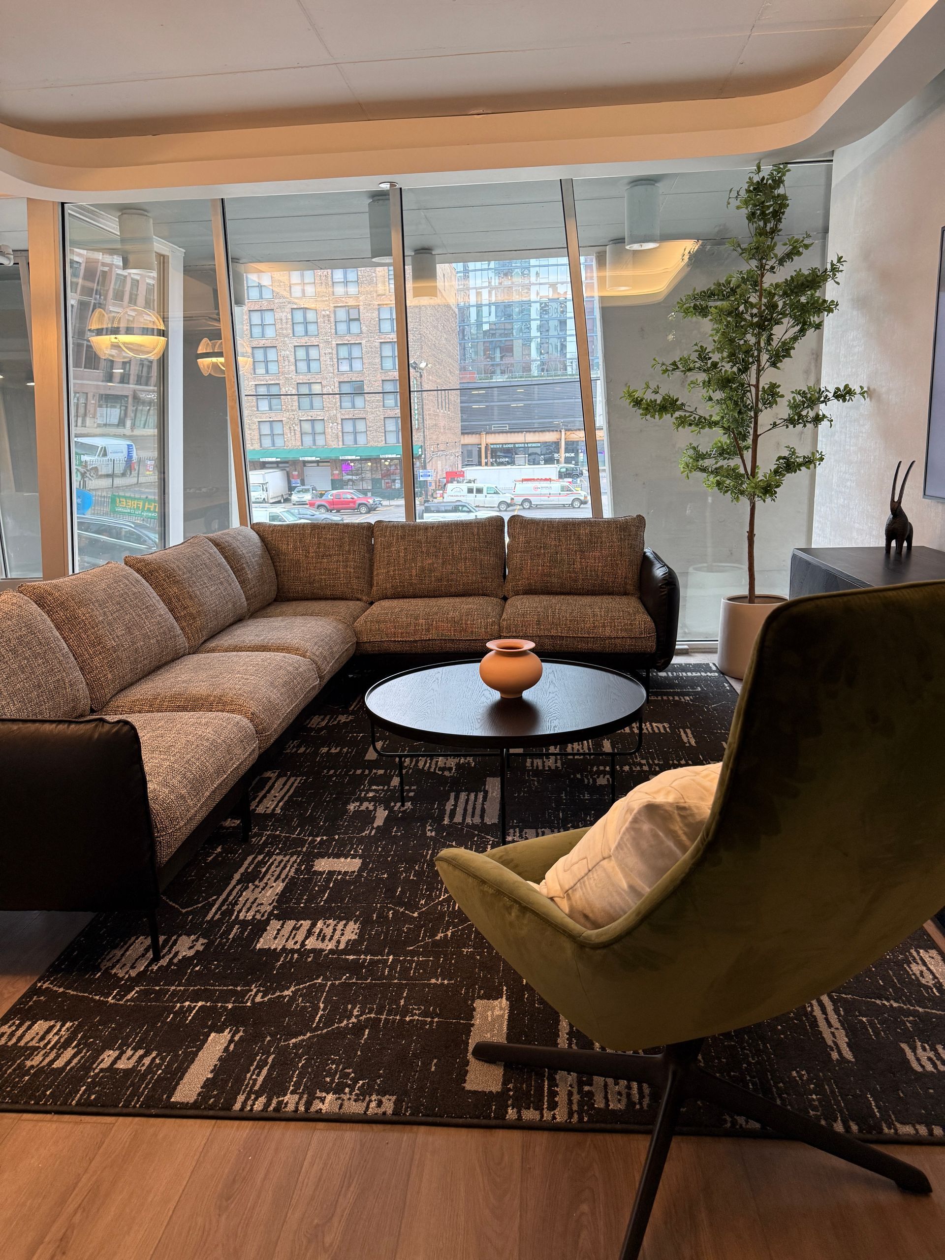 Office space: cubicles, waiting area with blue chairs, TV, and decorative lighting. Two people in the area.
