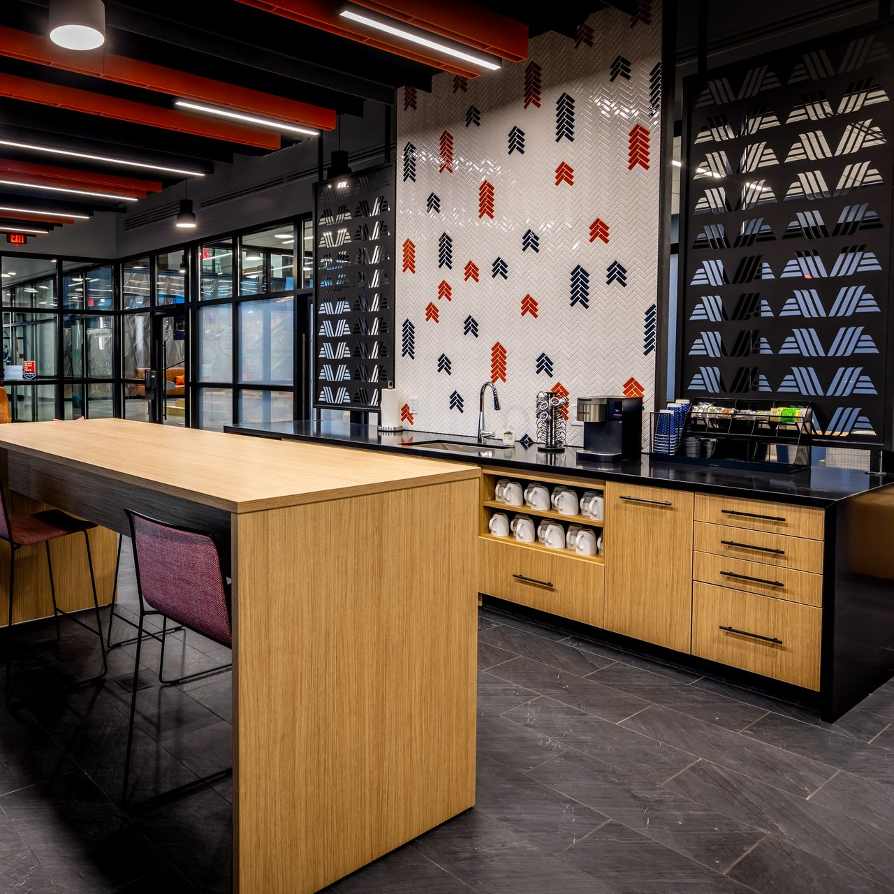 Modern café interior with wooden tables, black chairs, and patterned wall decor