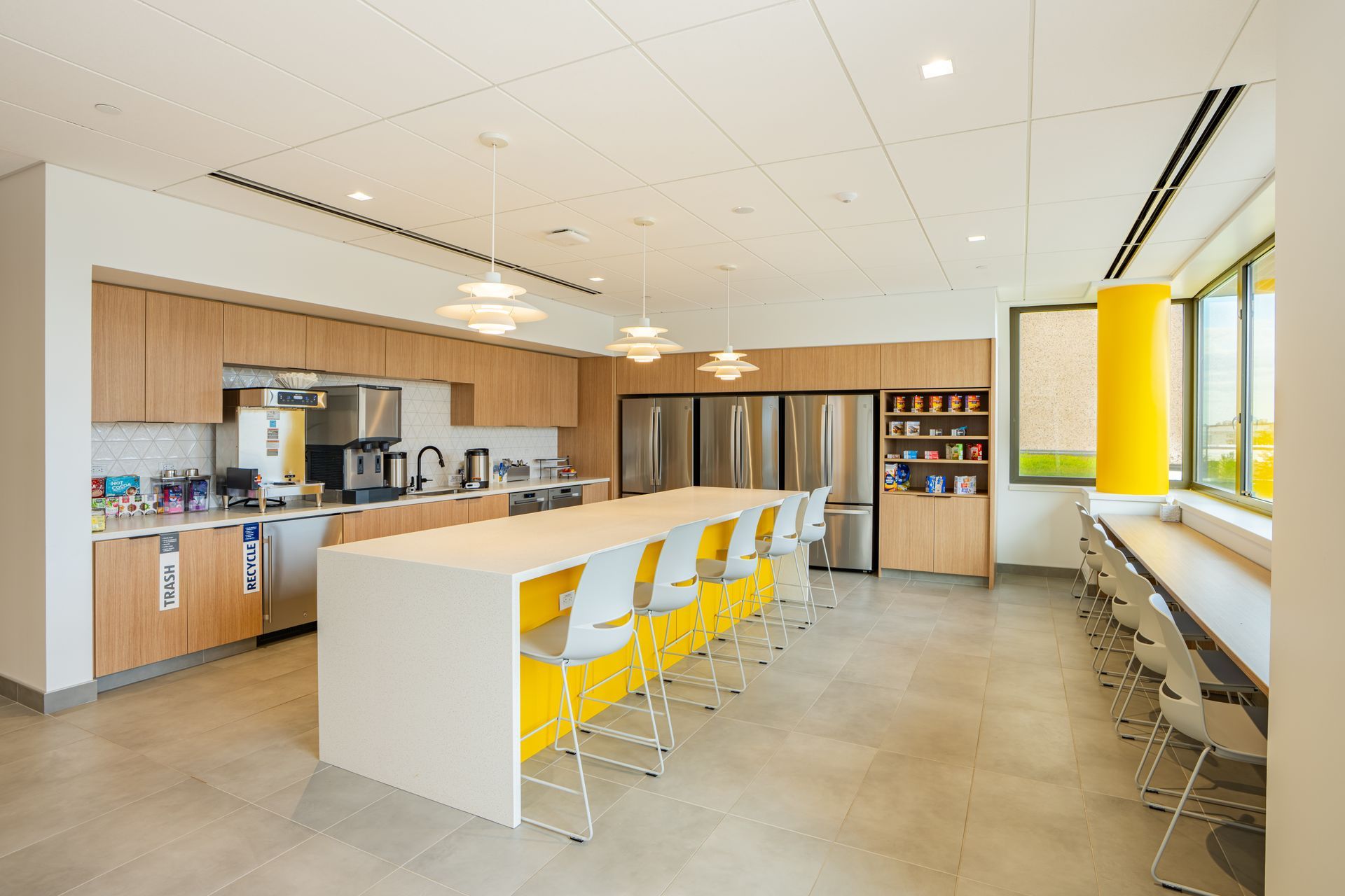 Office workspace with cubicles, windows, and overhead lighting.