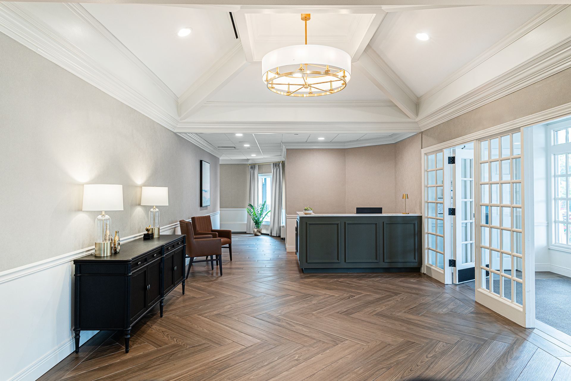 Reception area with dark wood floors, a dark green reception desk, and French doors.