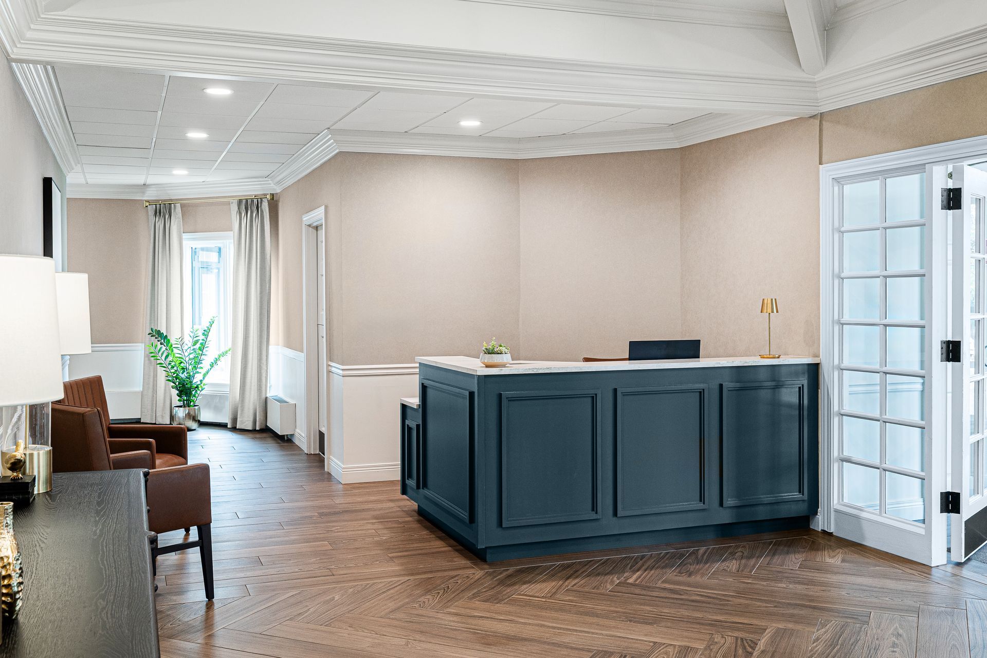 Reception area with blue front desk, wooden floor, and a double door.