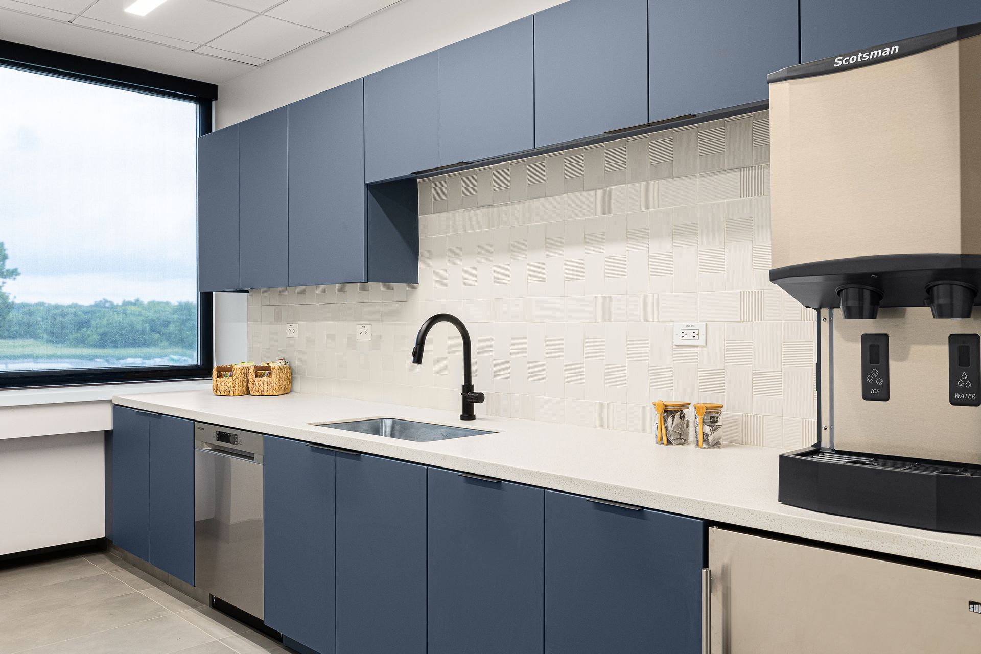 Office breakroom with blue cabinets, a sink, and a coffee machine.