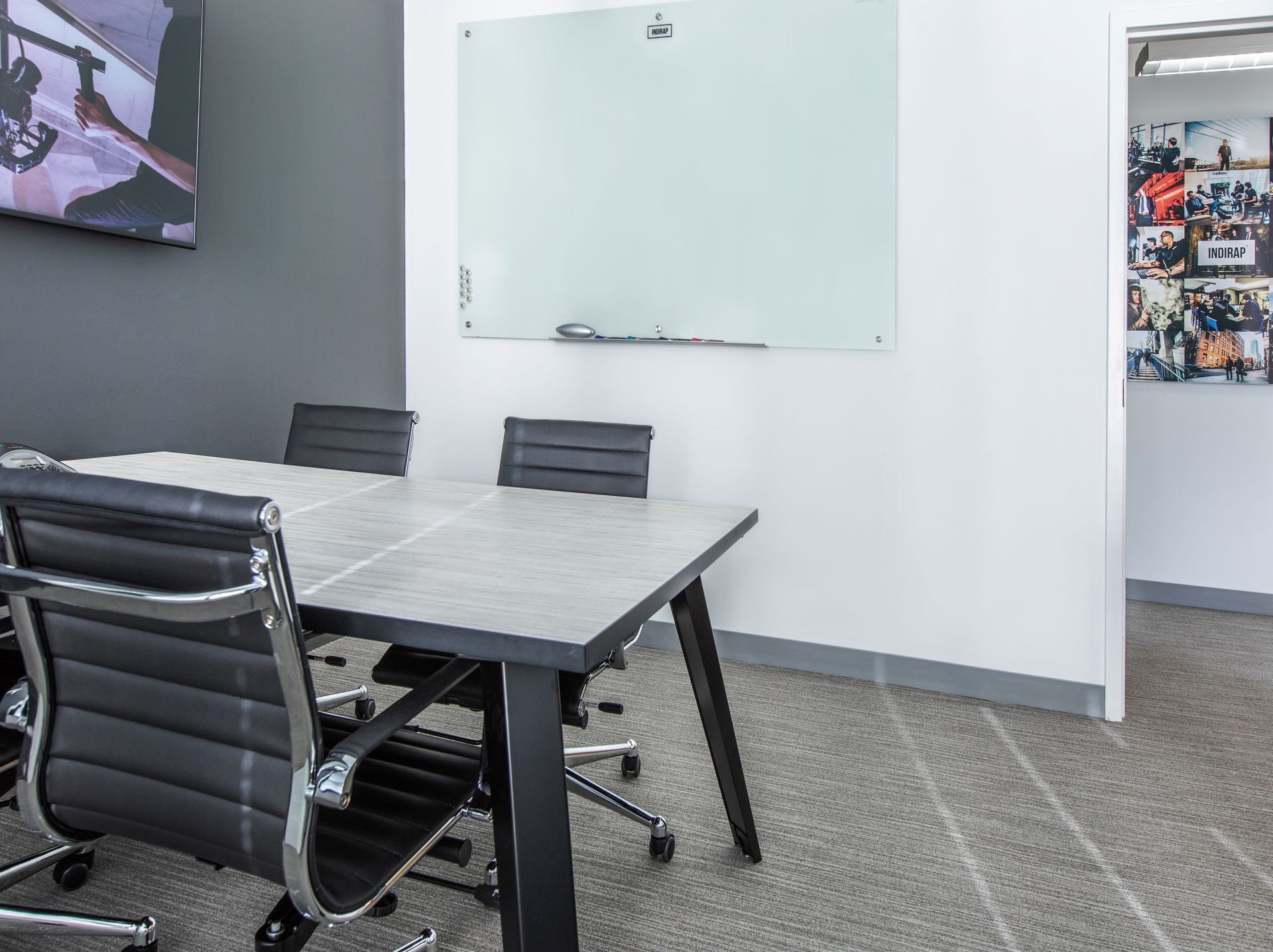 Conference room with table, chairs, whiteboard, and open doorway.