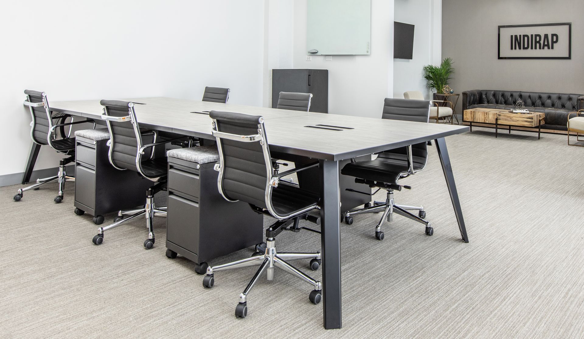Conference room with large table, office chairs, and rolling file cabinets. Neutral colors, modern style.