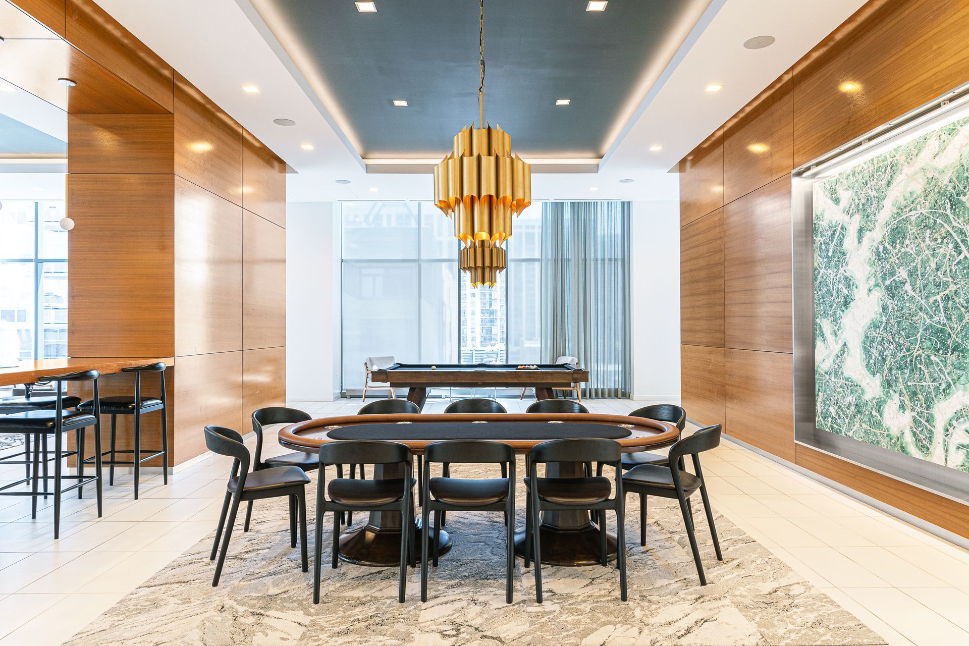 A luxurious game room with a poker table, a pool table, and a large golden chandelier.