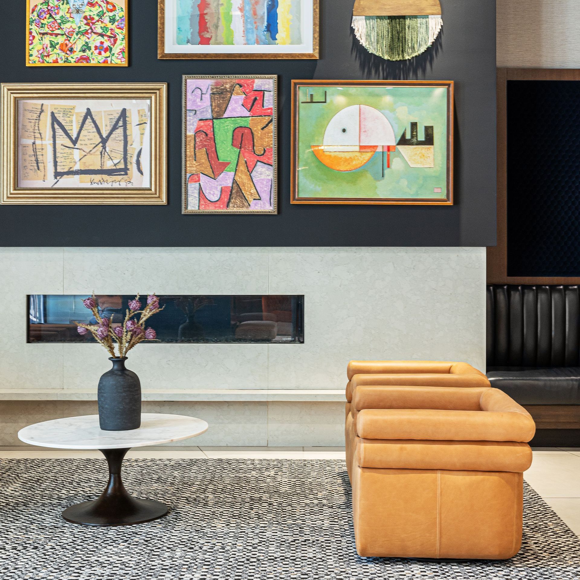 Living room with art, a fireplace, round table with flowers, and two brown leather chairs.