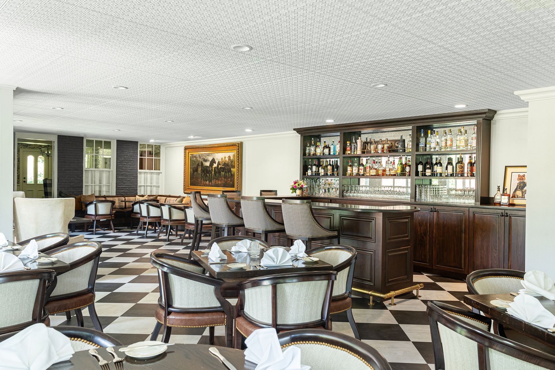 Elegant restaurant interior with a bar and checkered floor, tables set for dining.