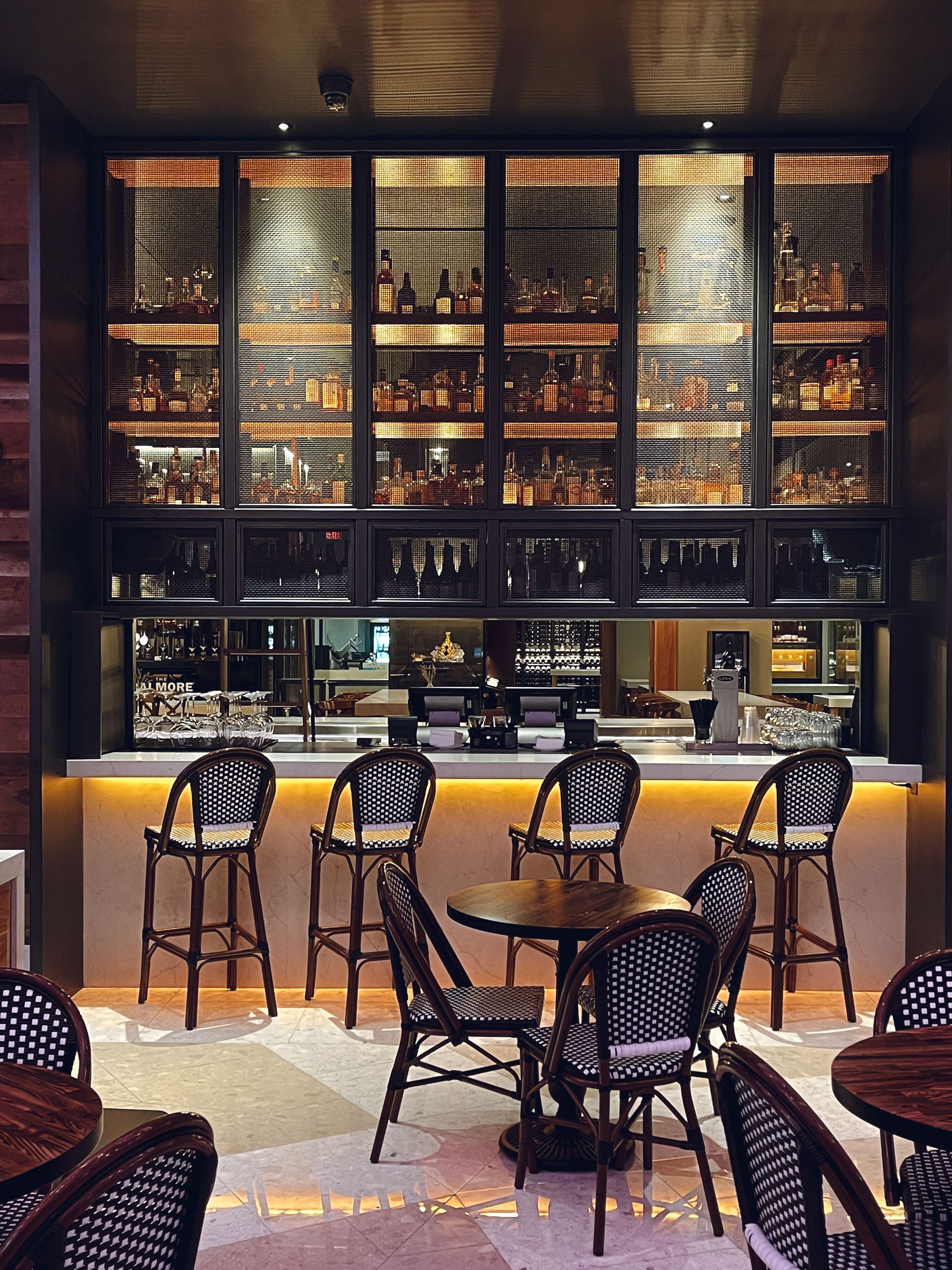 Stylish bar interior with tall stools, glowing shelves of bottles, and warm ambient lighting