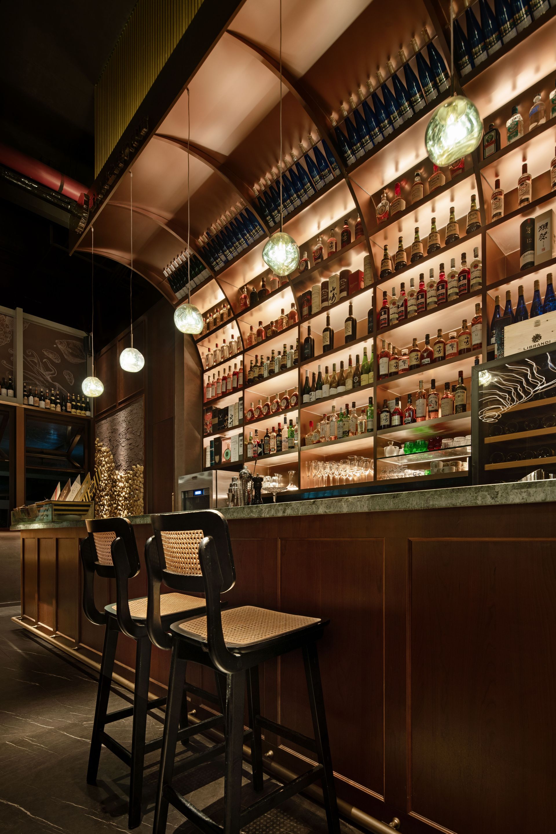 Stylish bar interior with tall stools, glowing shelves of bottles, and warm ambient lighting