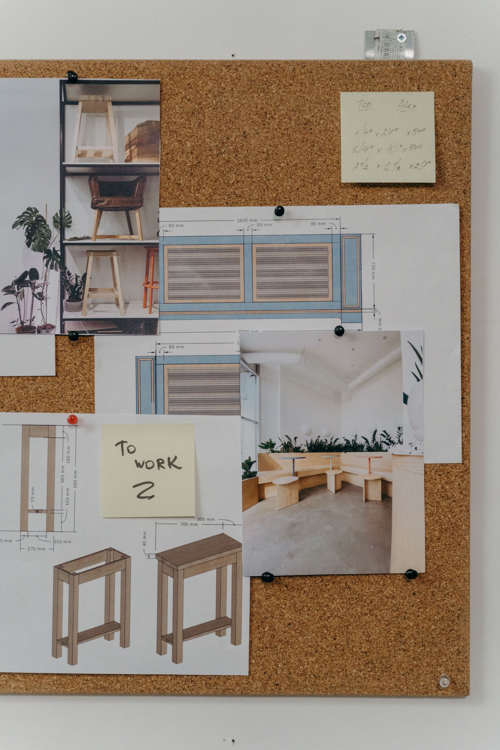 Mood board on a corkboard with interior design sketches, fabric swatches, and stool concepts.