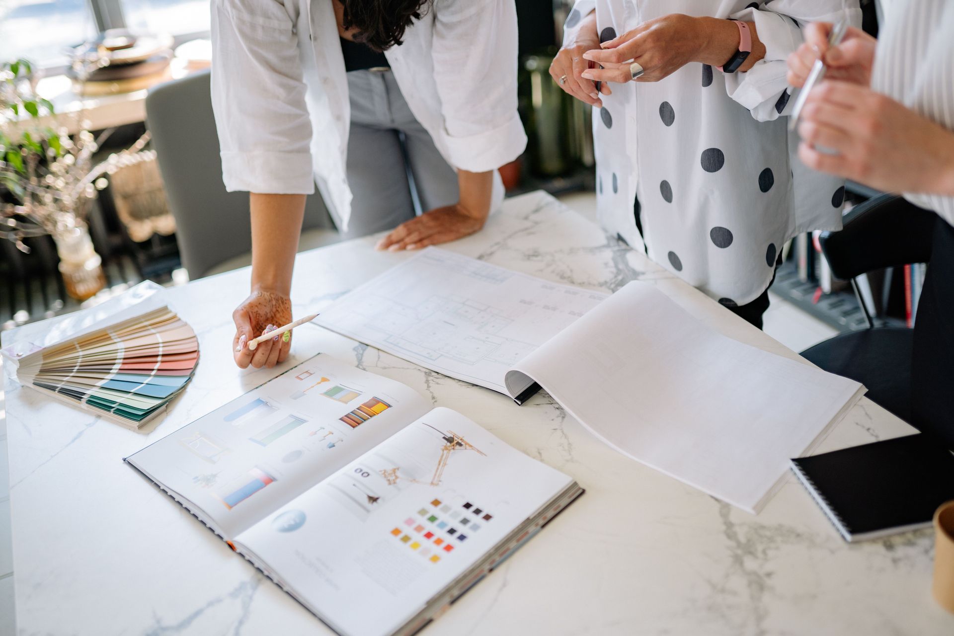 People reviewing color swatches and design mockups on a marble table