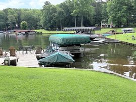 Orange floating workboat spraying water in a green harbor beside a dock and pontoon line