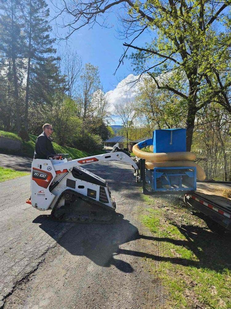 A man is driving a small bulldozer down a road.
