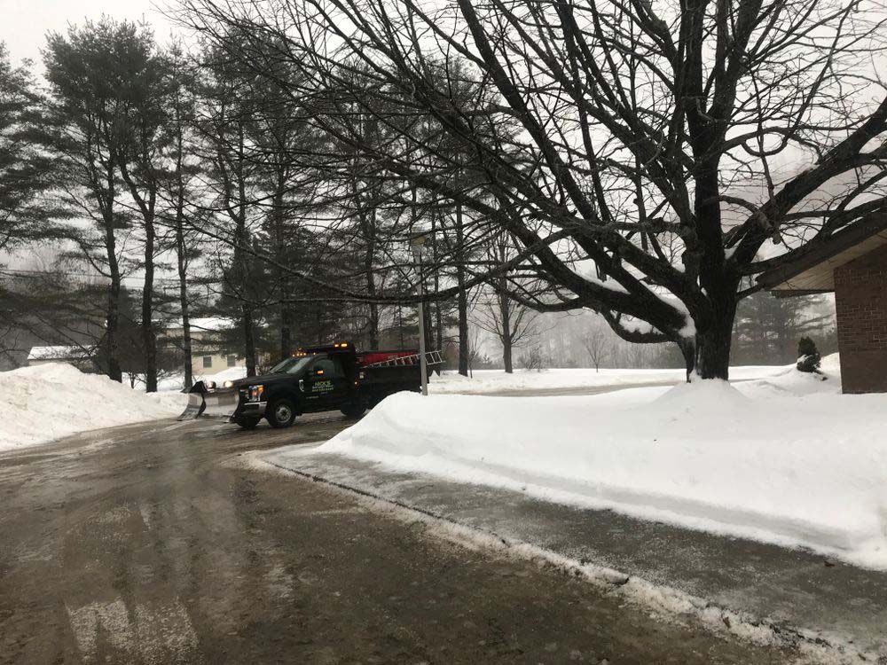 A truck is parked on the side of the road in the snow.