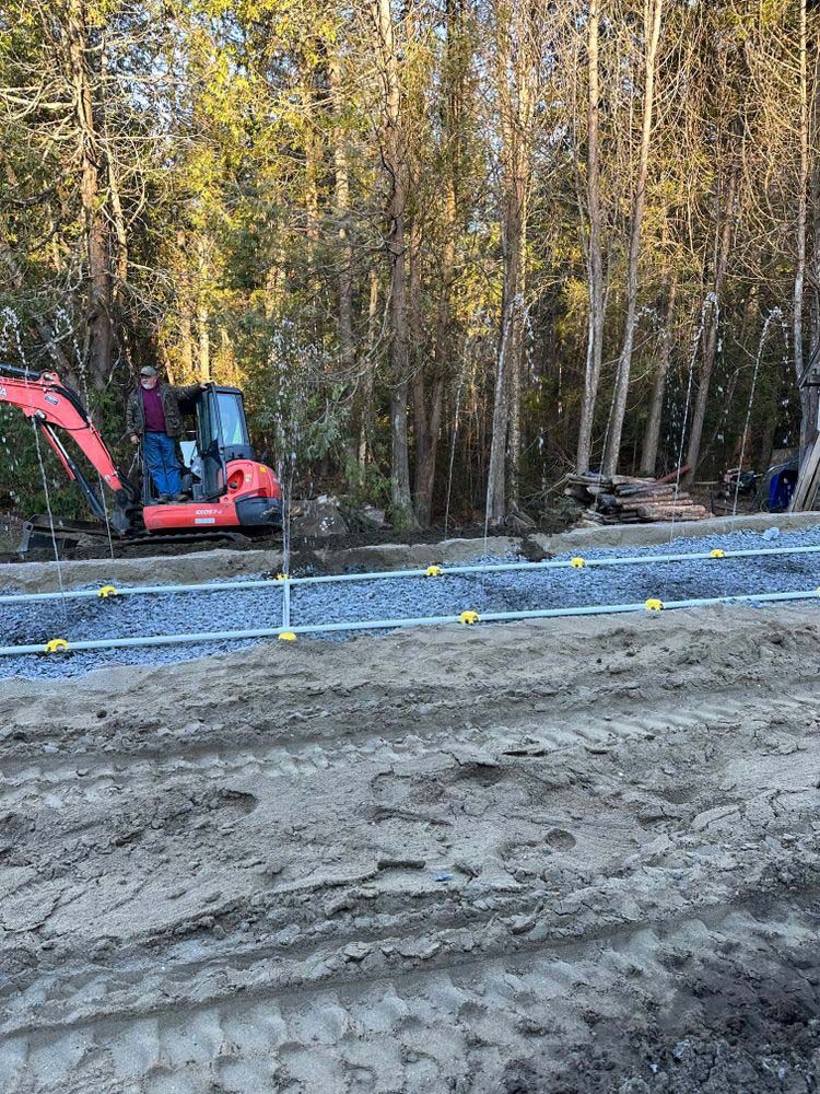 A red excavator is driving down a dirt road in the woods.
