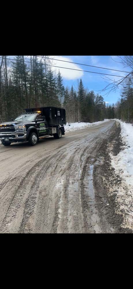A dump truck is driving down a snowy road.