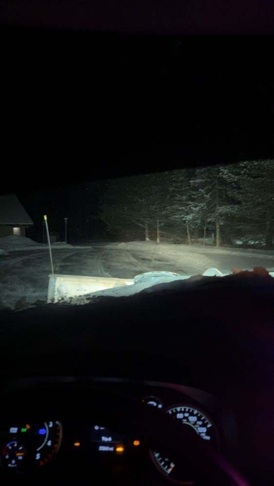 A person is driving a car at night in the snow.