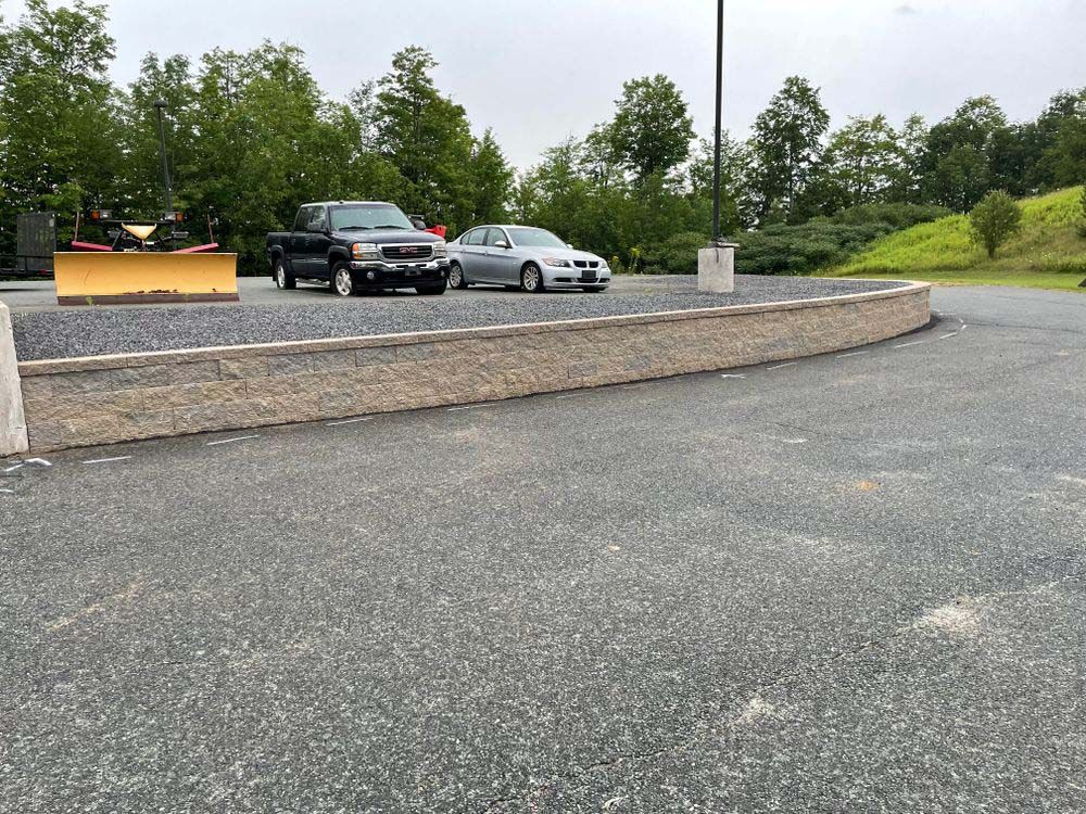 Two cars are parked in a parking lot next to a wall.