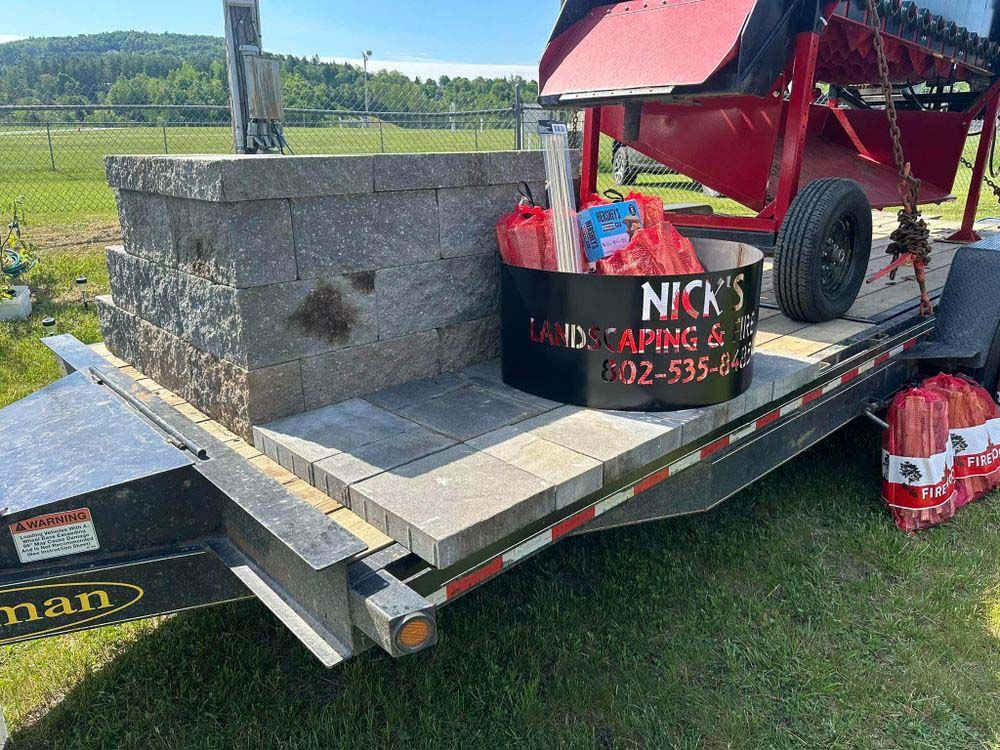 A trailer with a bucket of fireworks on it is parked in a field.